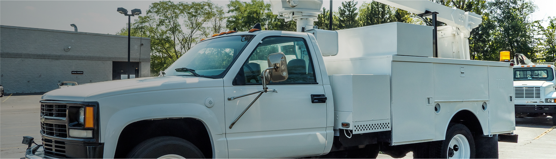 White utility truck parked in lot with service body and yellow beacon